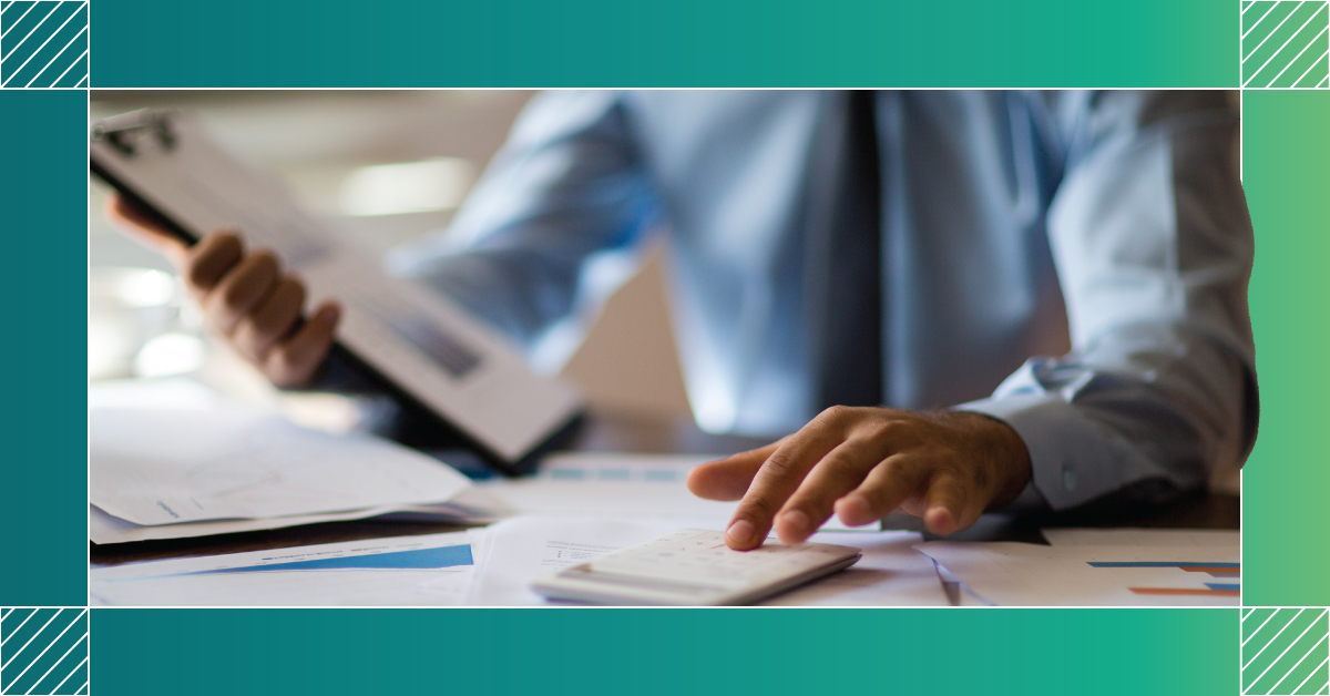 Blurred image of person in business wear typing on calculator and holding a clipboard