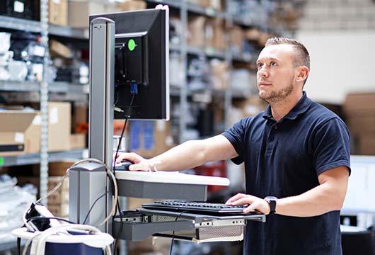 Engineer Looking at Desktop in Warehouse