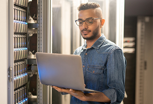 Male engineer with laptop working in data center