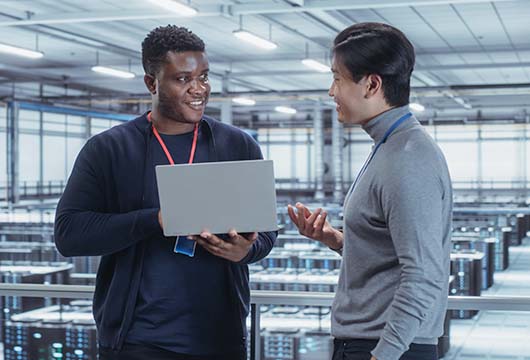 Engineers Communicate While Holding Laptop