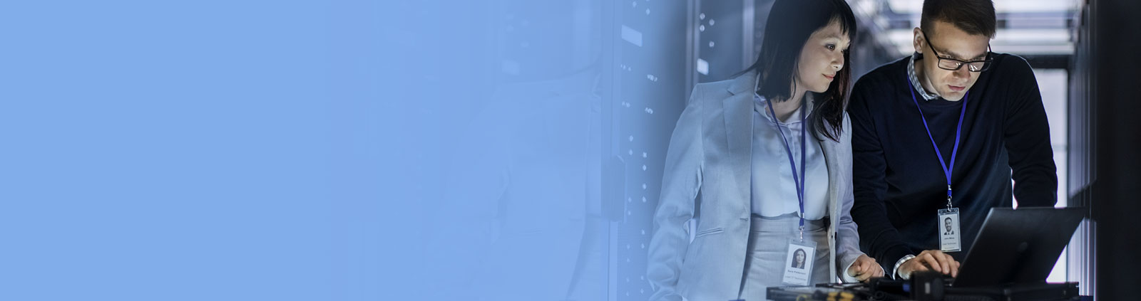 Female & male viewing laptop in data center