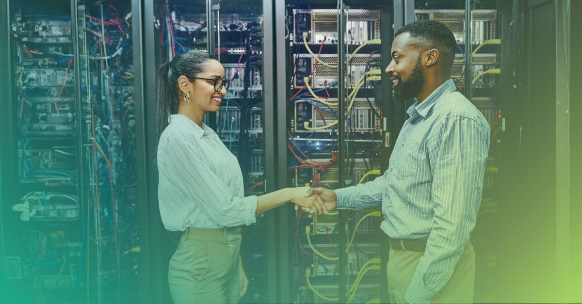 An image of a female and male engineer in a data center shaking hands