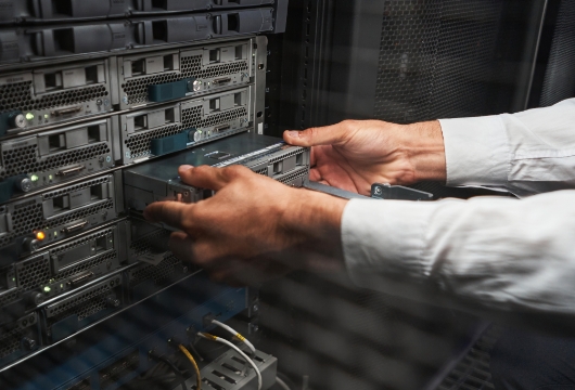 An image of two hands pulling a part from an equipment rack