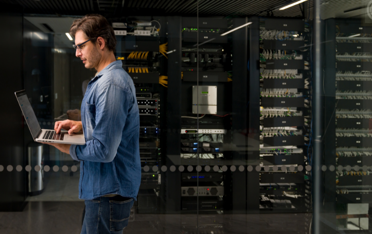 An image of a male on a laptop within a data center
