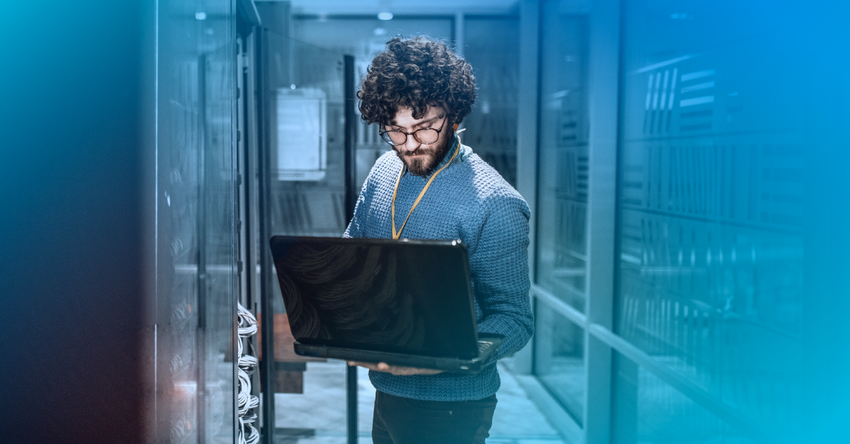 Male standing in data center on a computer with a blue gradient